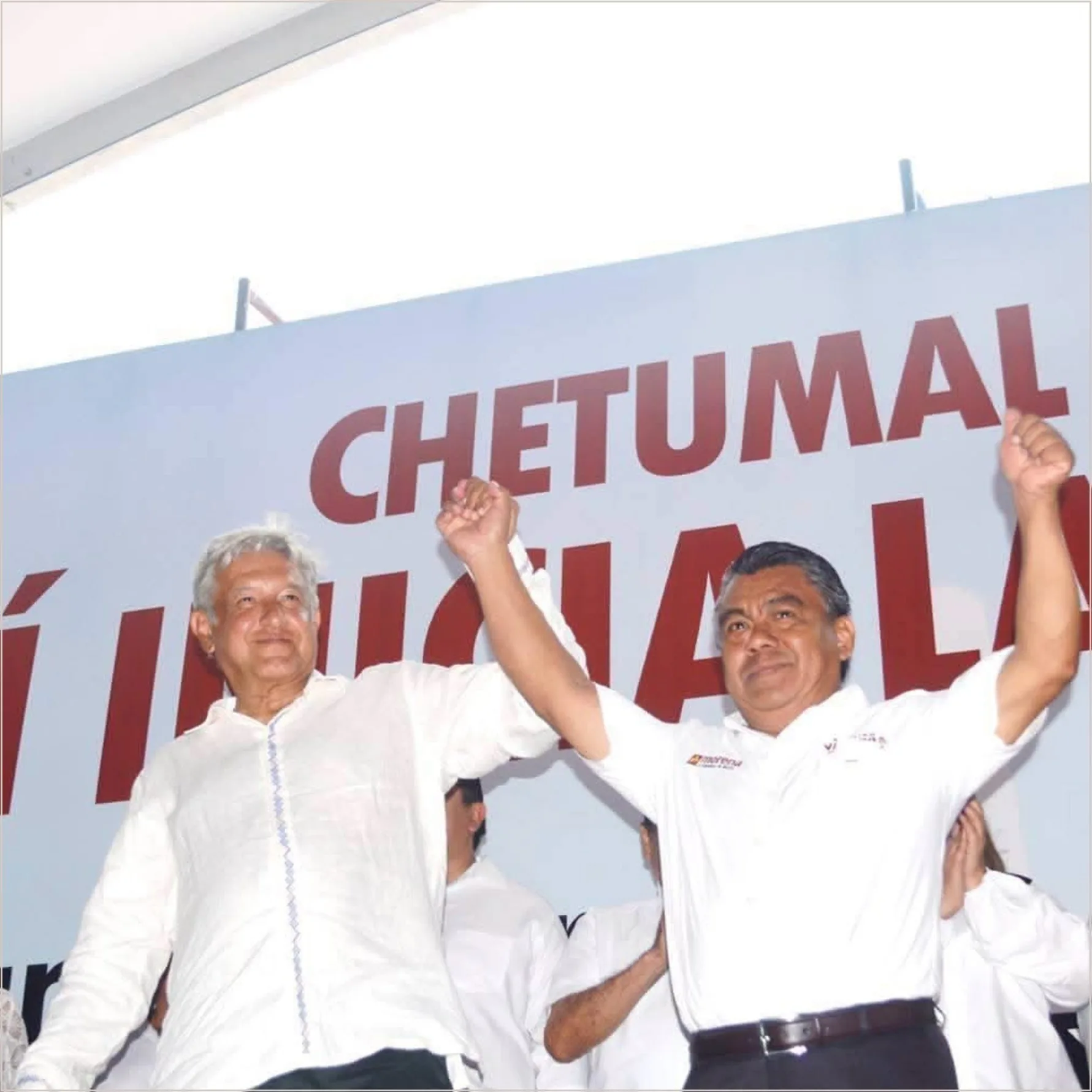 Rivelino Valdivia Villaseca levanta el brazo junto a Andrés Manuel López Obrador durante un acto político en Chetumal